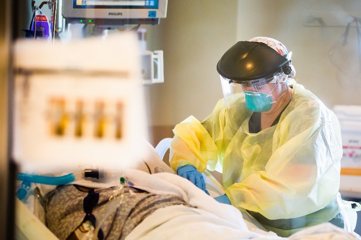 Doctor in yellow protective gear treating a patient