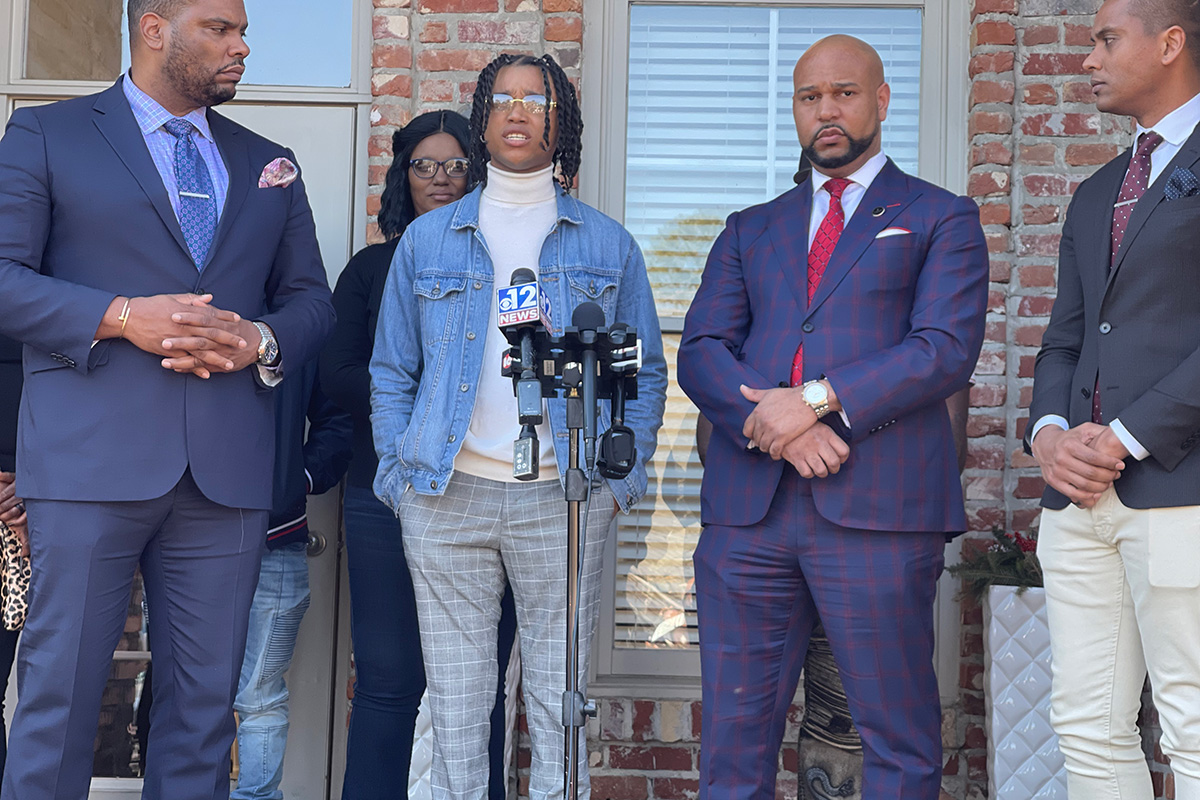 Fed Ex driver D'Monterrio Gibson speaking at a mic with four other men behind him.