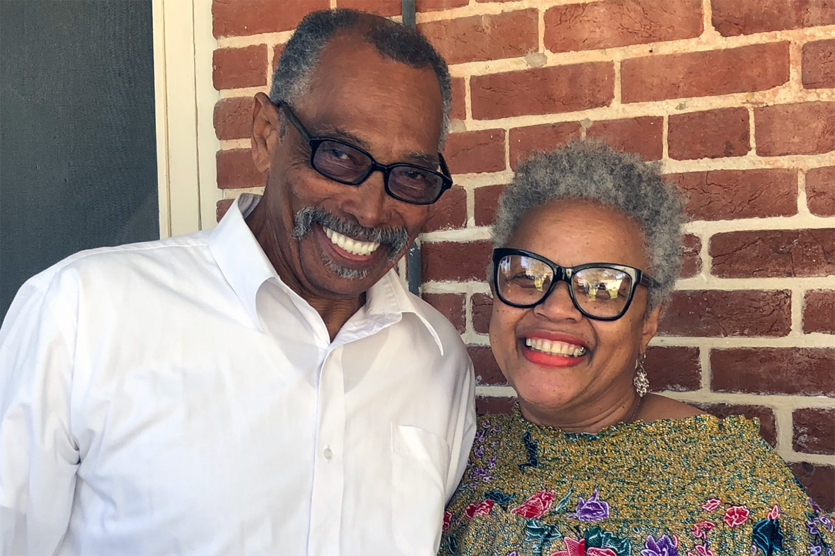Greg and Deborah Cosey smiling in front of a brick wall