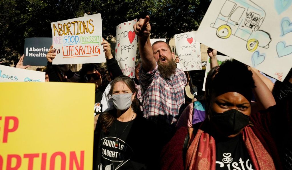 Several abortion rights supporters at a rally holding various signs