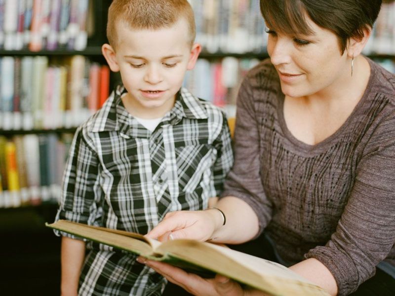 A teacher and student look at a book together
