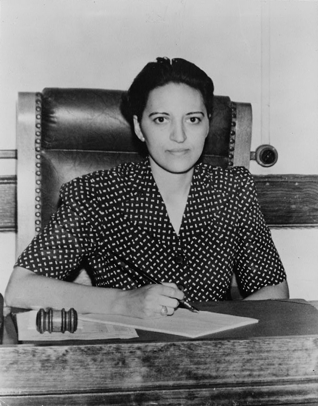 Black and white video of a woman in a polka dot dress sitting at a desk