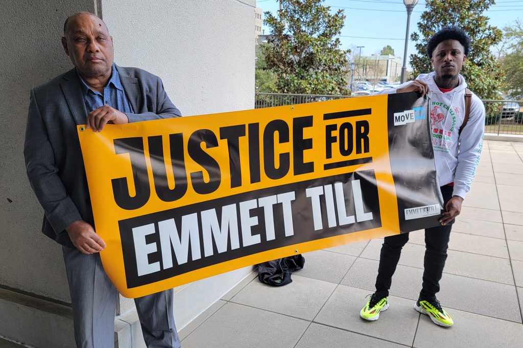 Two men hold a yellow and black banner that reads Justice for Emmett Till