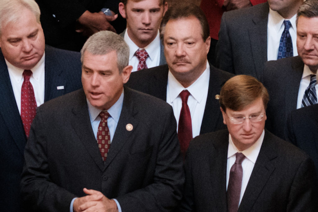 a photo of Speaker Philip Gunn and Gov. Tate Reeves surrounded by other lawmakers