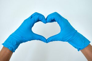 Two hands in blue gloves making a heart sign