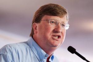 a photo of Mississippi governor Tate Reeves speaking at a microphone