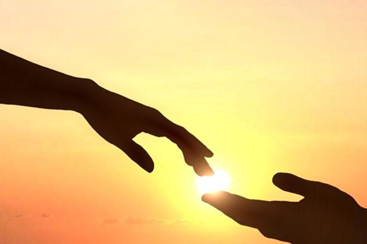 Two hands reaching towards each other with a sunset in the background