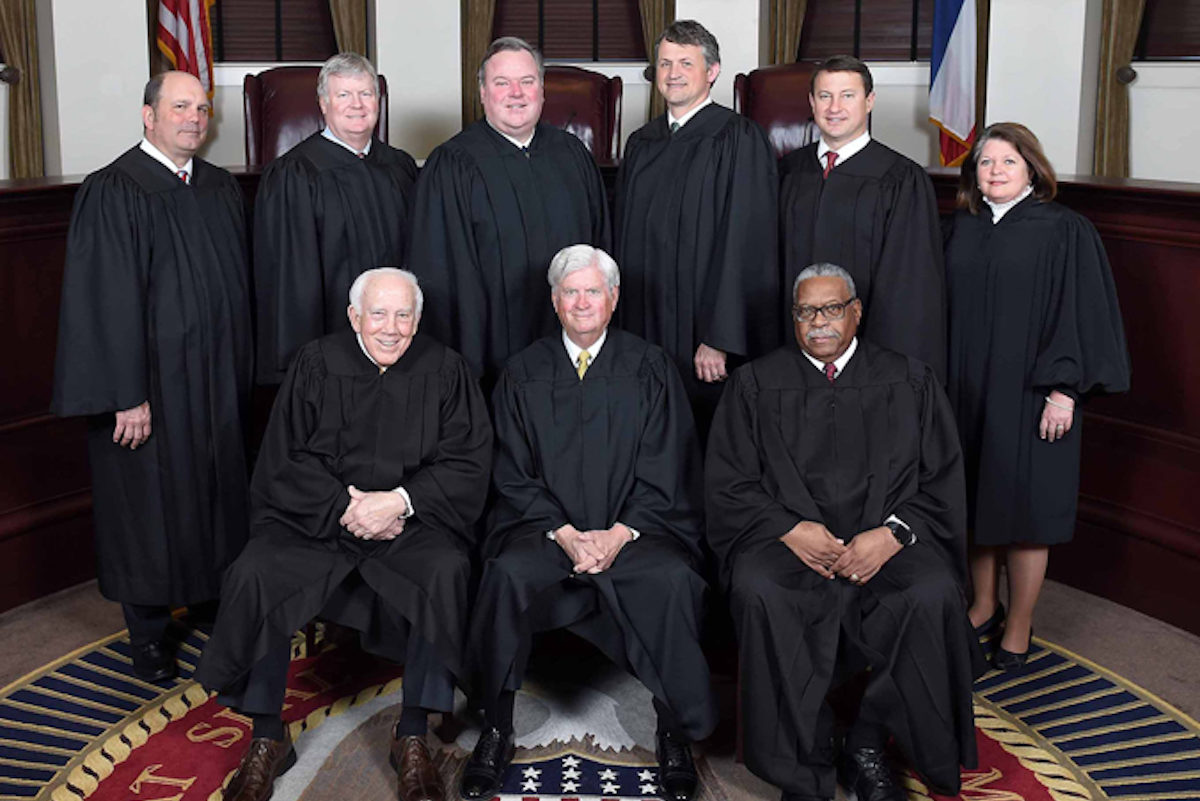 a photo shows seven white men, one white woman and one black man all dressed in black robes
