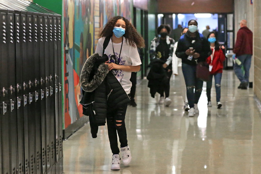 Students, masked, walking down a high school hallway