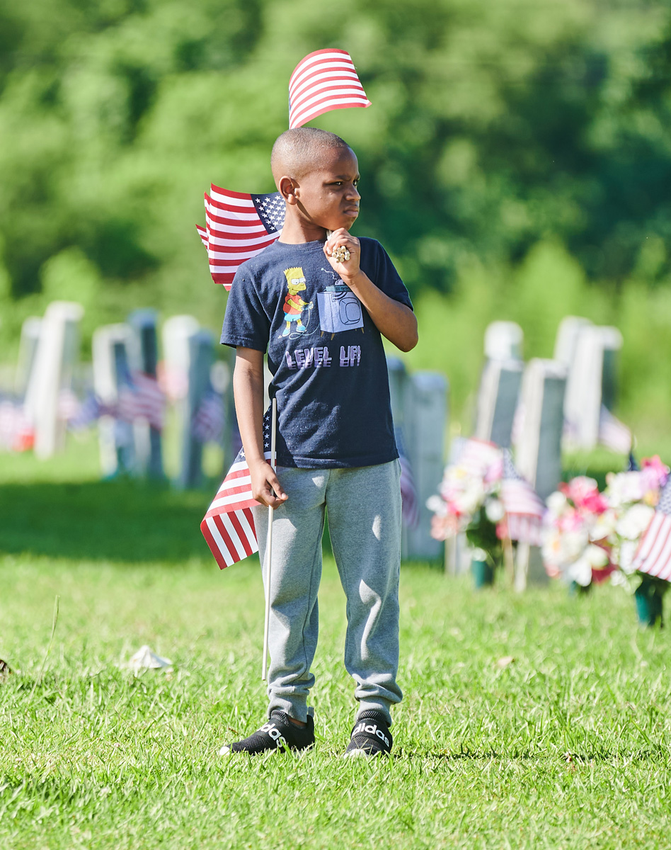 A child walks through a graveyard with several US Flags
