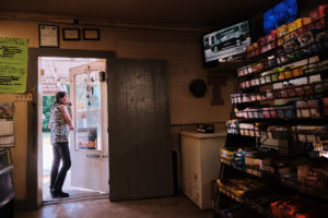 A woman looks out the front door of a small community grocery