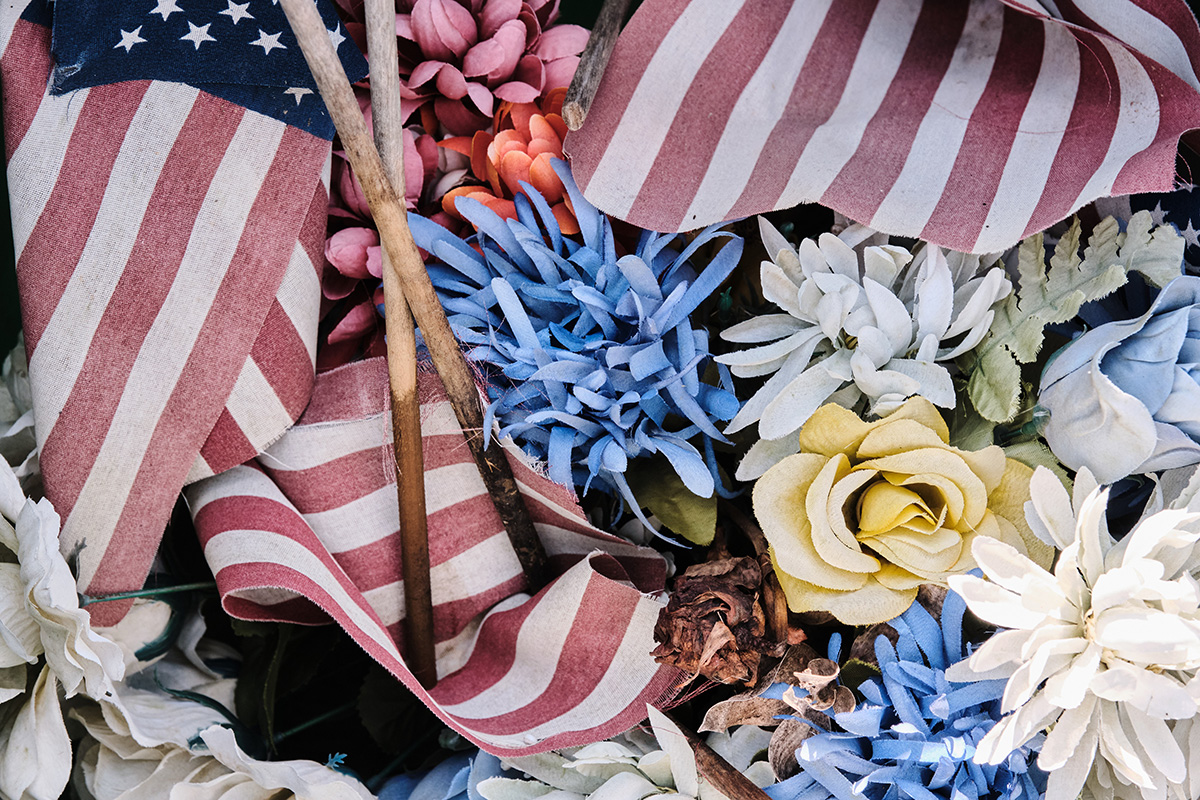 A pile of faded US Flags and faux flowers