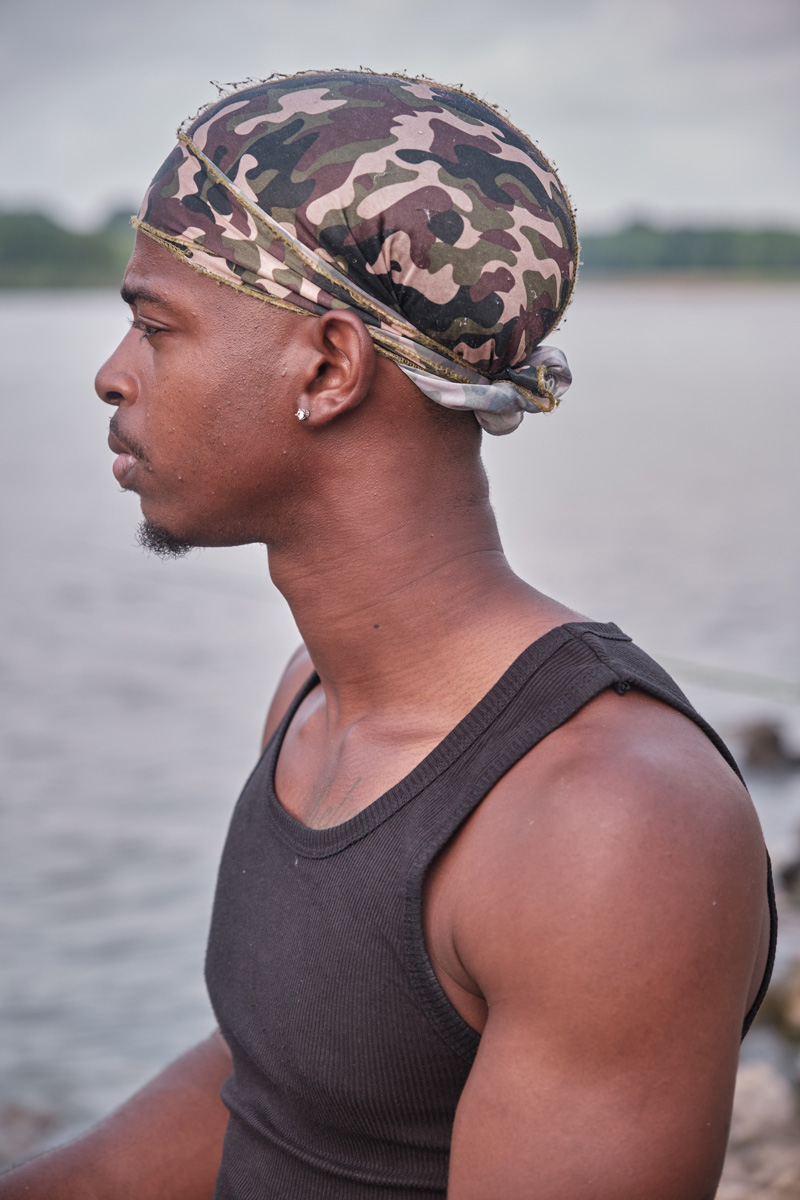 A man in a black tank top and camo head covering