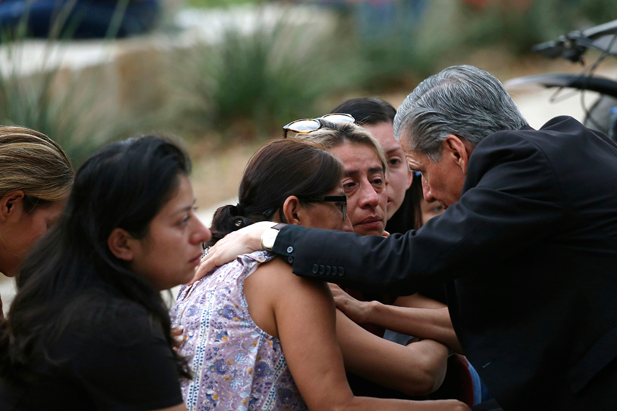 Grieving people gather with an archbishop