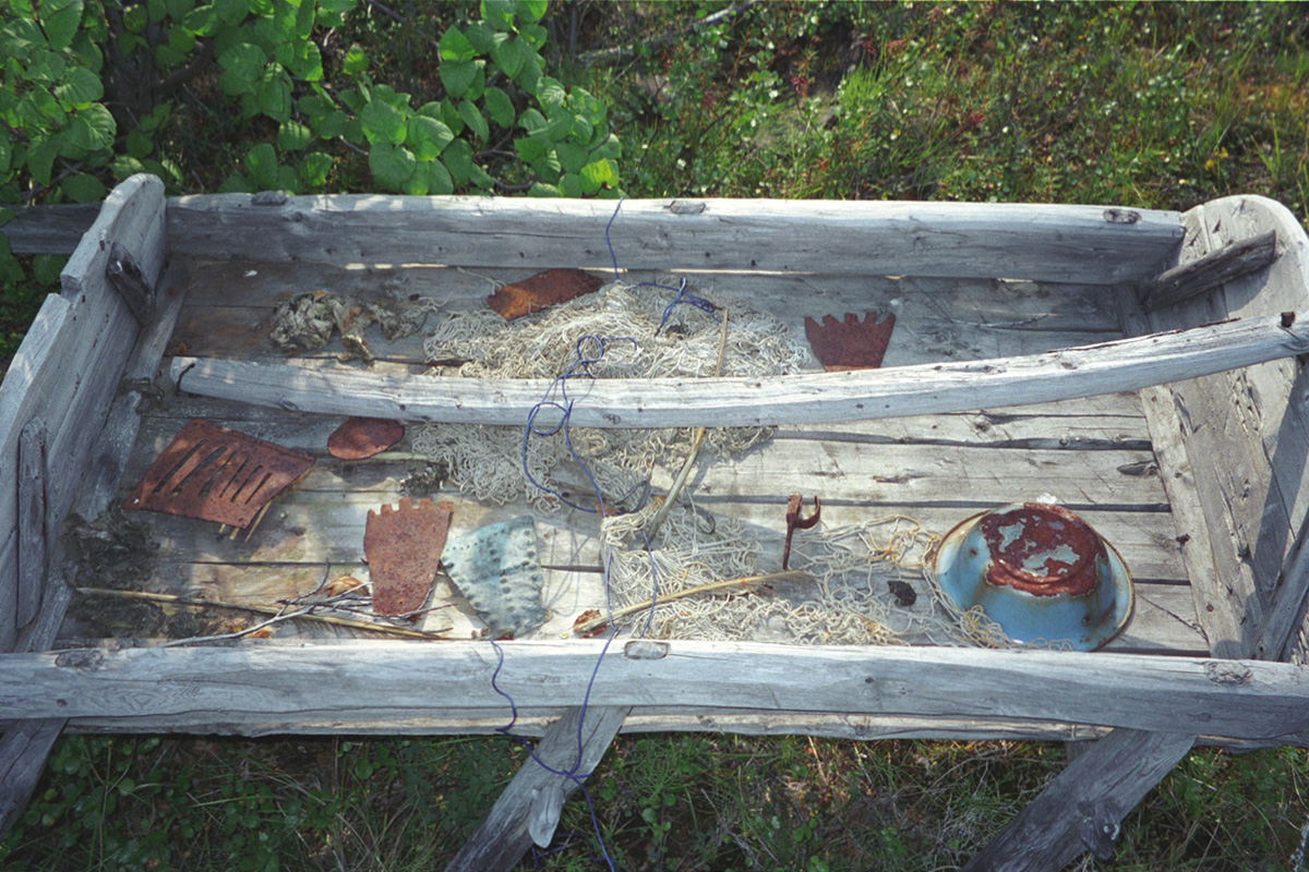 A number of small items are strewn across the top of a sled sitting in a field.