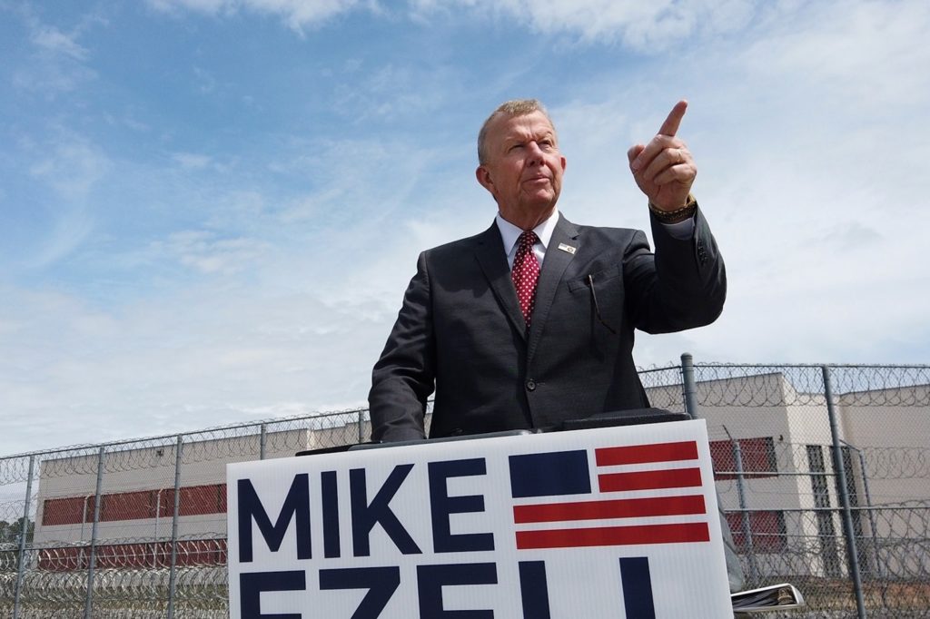 a photo of Mike Ezell pointing a finger to the sky on a bright day