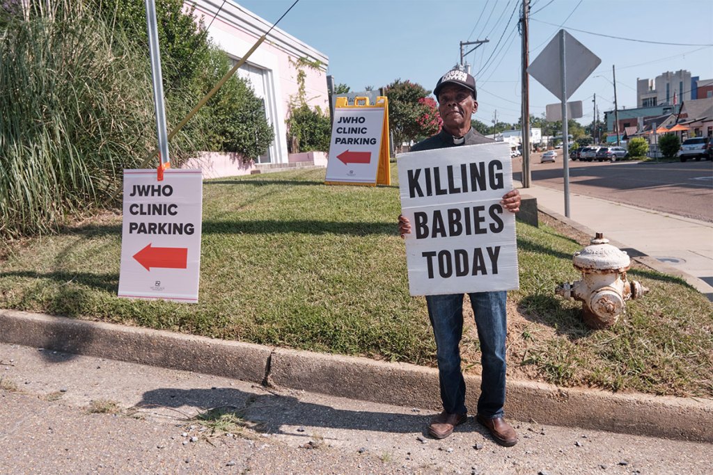 An abortion protester stands with a sign "Killing Babies Today"