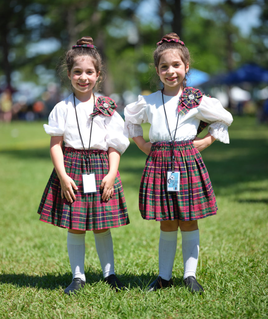 Twin girls in red tartan skirts pose together