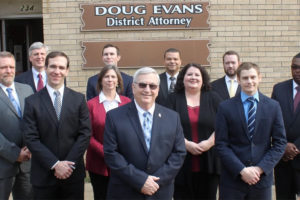 Group photo of people in front of a sign that reads Doug Evans, District Attorney