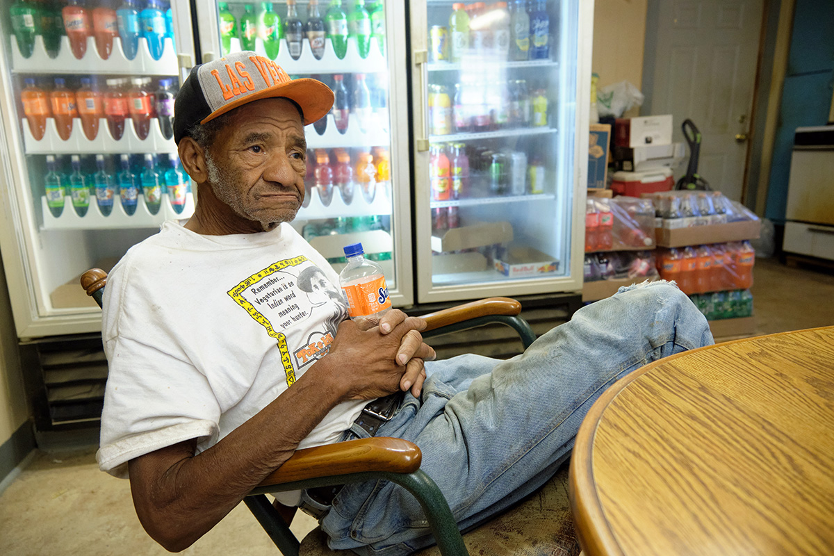 A man in a Las Vegas baseball cap leans back with an orange Sunkist soda in his hands
