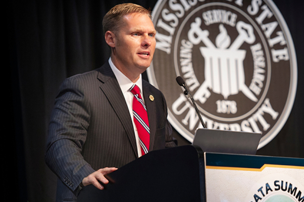 Michael Guest speaking at a podium