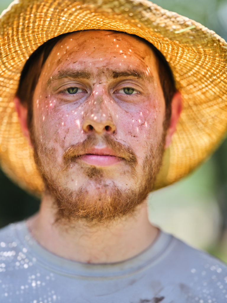 a man wearing a straw hat with dirt on his face