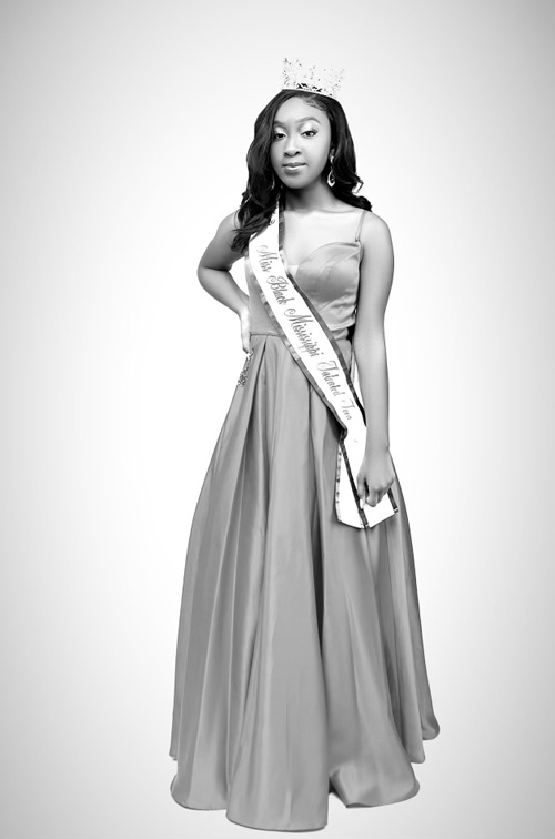Black and white photo of a woman in floor length gown and crown