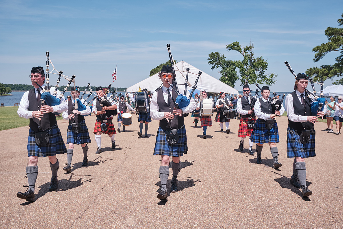 Bagpipe players in blue tartan march in three lines