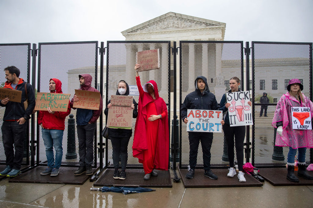 Abortion-rights protesters hold signs during a demonstration outside of the U.S. Supreme Court emergency fencing during a rainstorm
