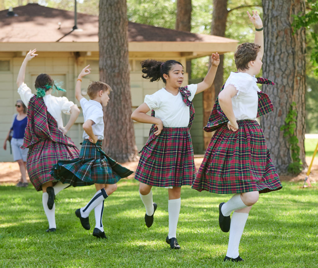 Four young dancers in tartan spin