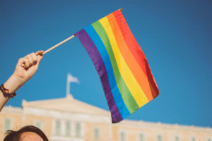 A rainbow flag is held aloft