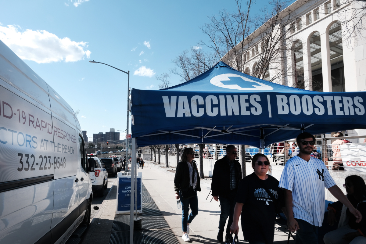people walk near a tent marked 'Vaccines | Boosters