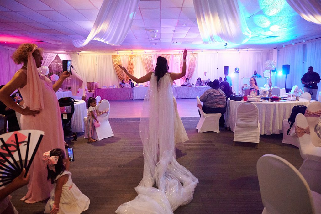 A person in a white dress dances in a colorfully lit room