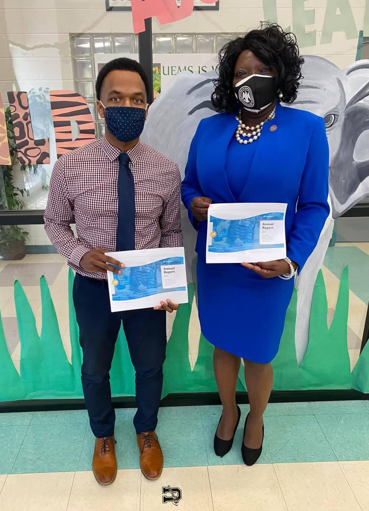 A man and a woman wearing medical masks post by a painted glass wall, holding paper certificates