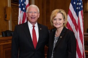 a photo shows Roger Wicker and Cindy Hyde-Smith posing together and smiling at the camera