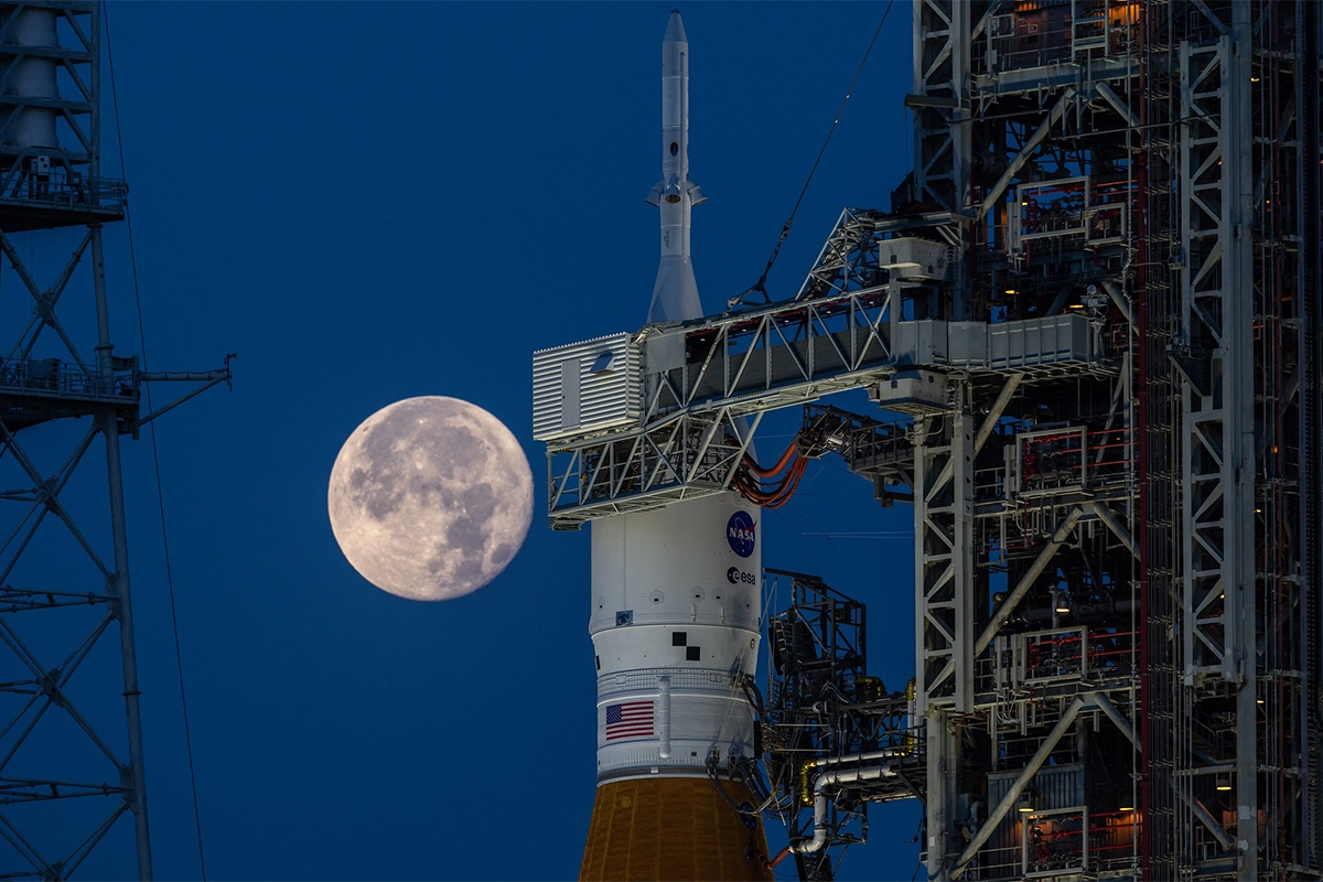The strawberry supermoon rises behind the Artemis 1 moon rocket on June 14, 2022.