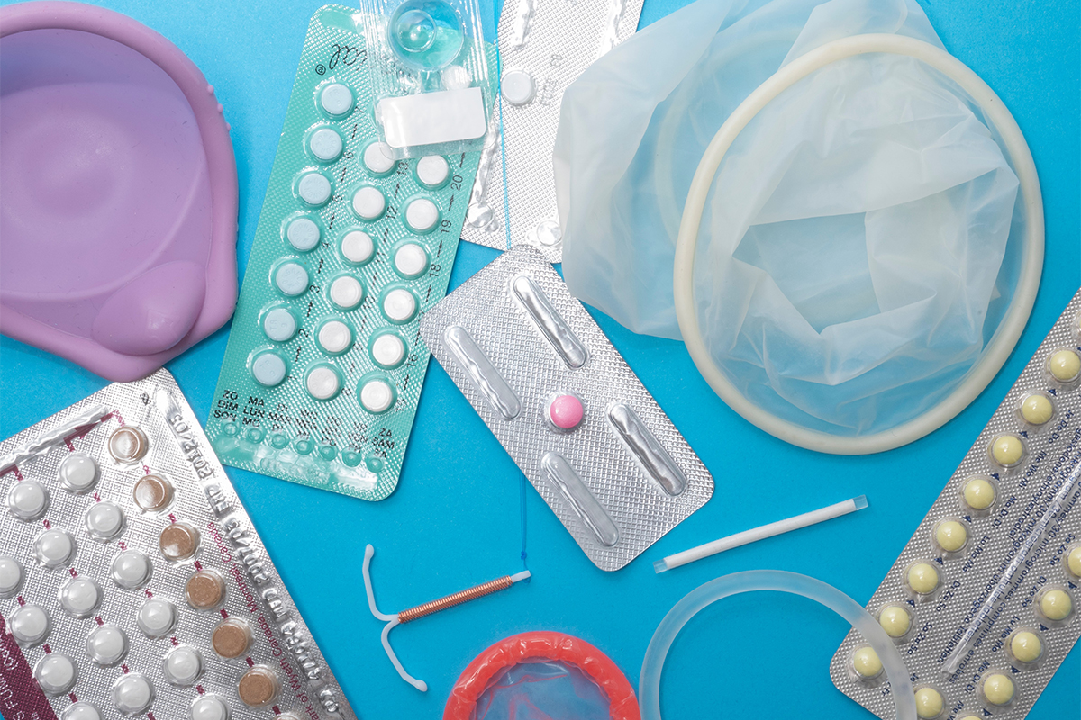Various contraceptive pills and devices sit on a blue background