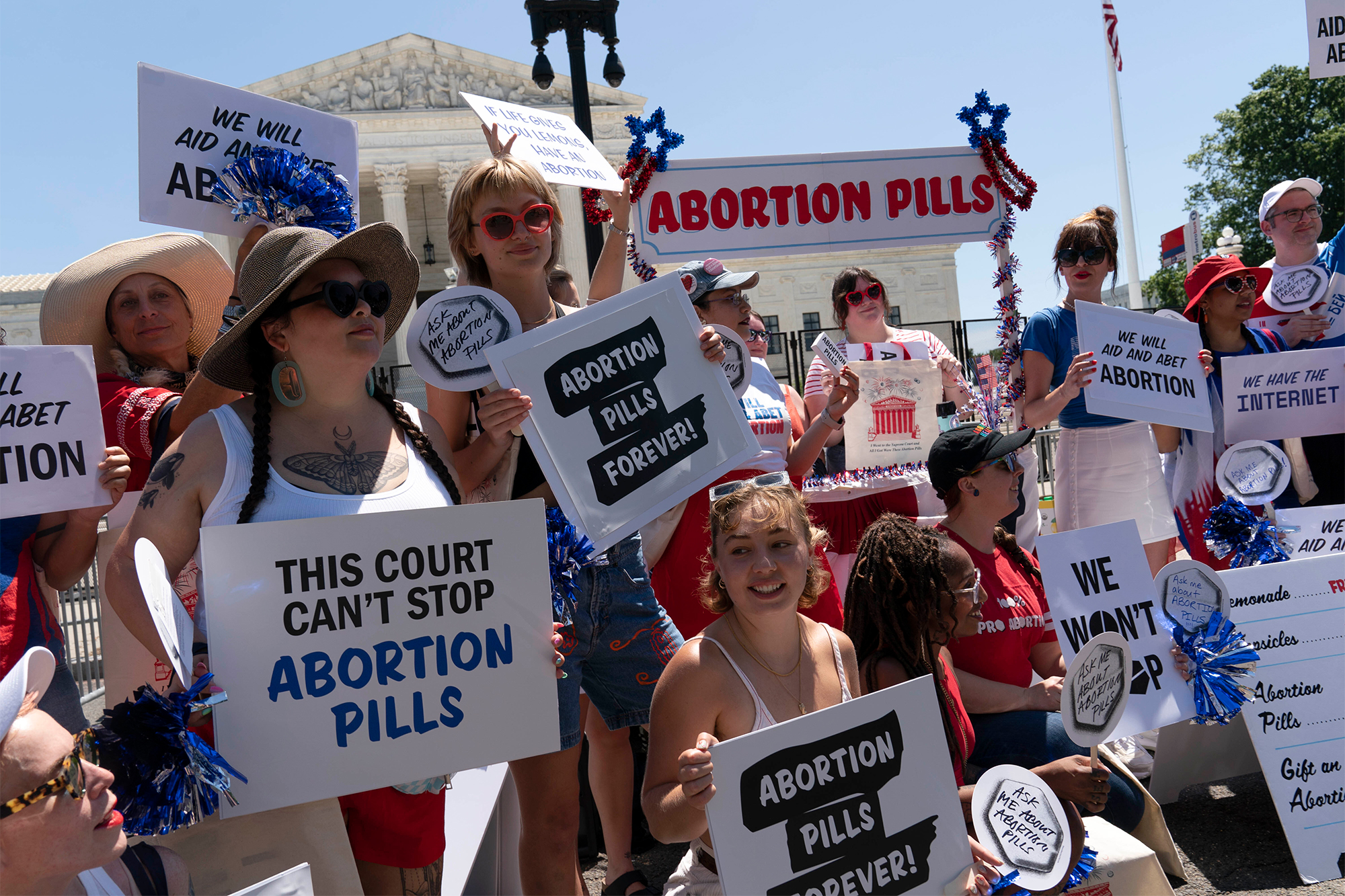 A crowd of women hold signs that say "Abortion Pills Forever"
