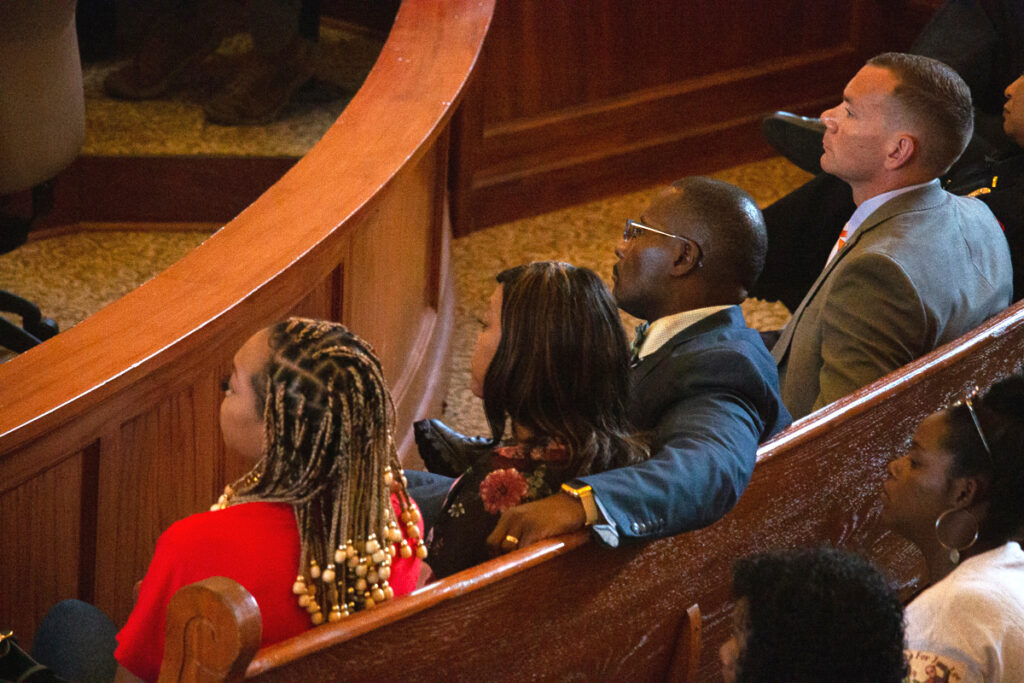 A back view of four people sitting on a courtroom bench