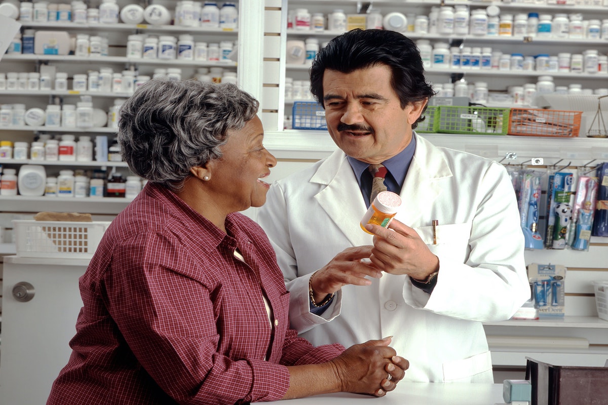 Stock photo of a white male pharmacist talking to an older black woman (cardiovascular disease)