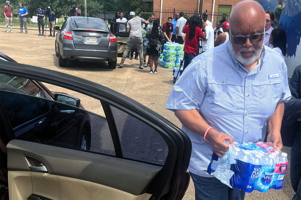 Bennie Thompson in a short sleeve blue shirt seen lifting water palettes into cars