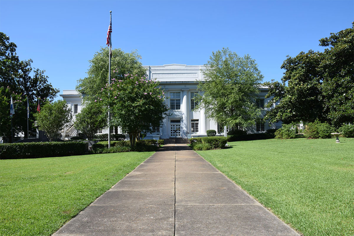 Courthouse of Pike County, Mississippi surrounded by green trees