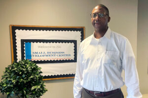Rickey Jones standing inside beside a sign that reads Welcome to JSU Small Business Development Center