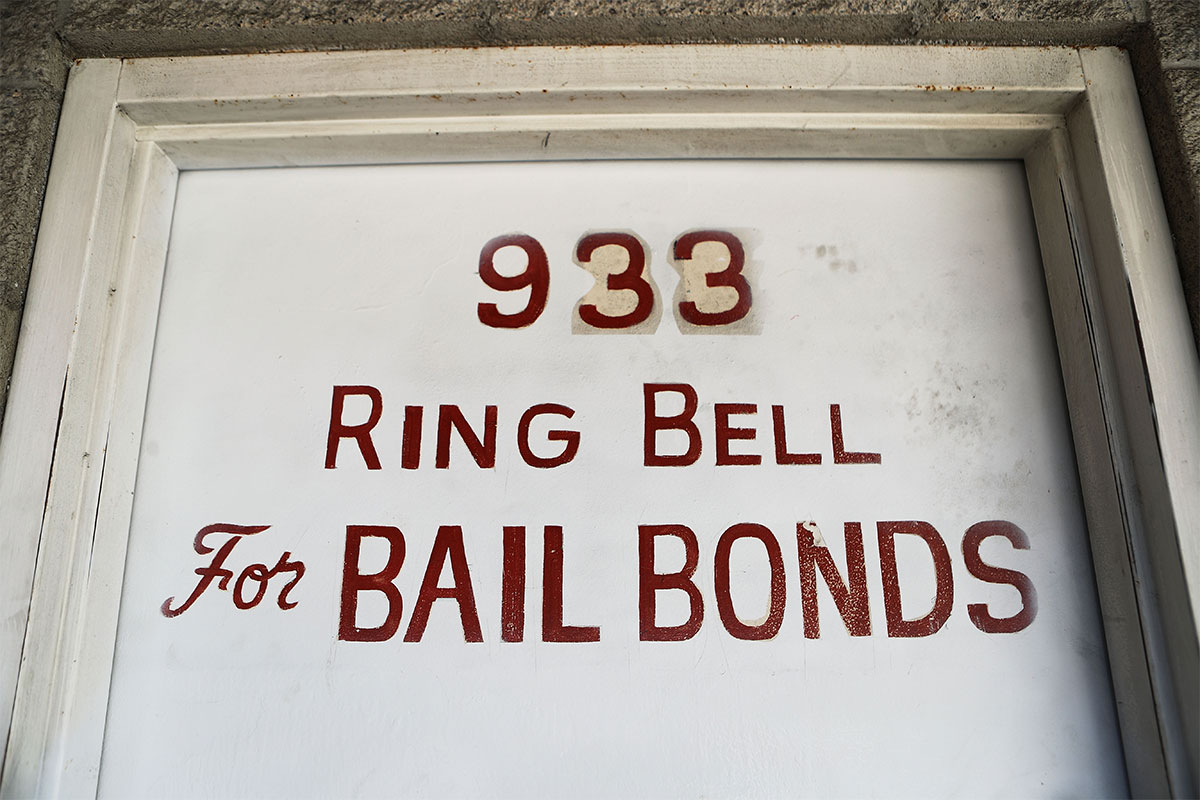 A white door says 'Ring bell for bail bonds,' in red font.