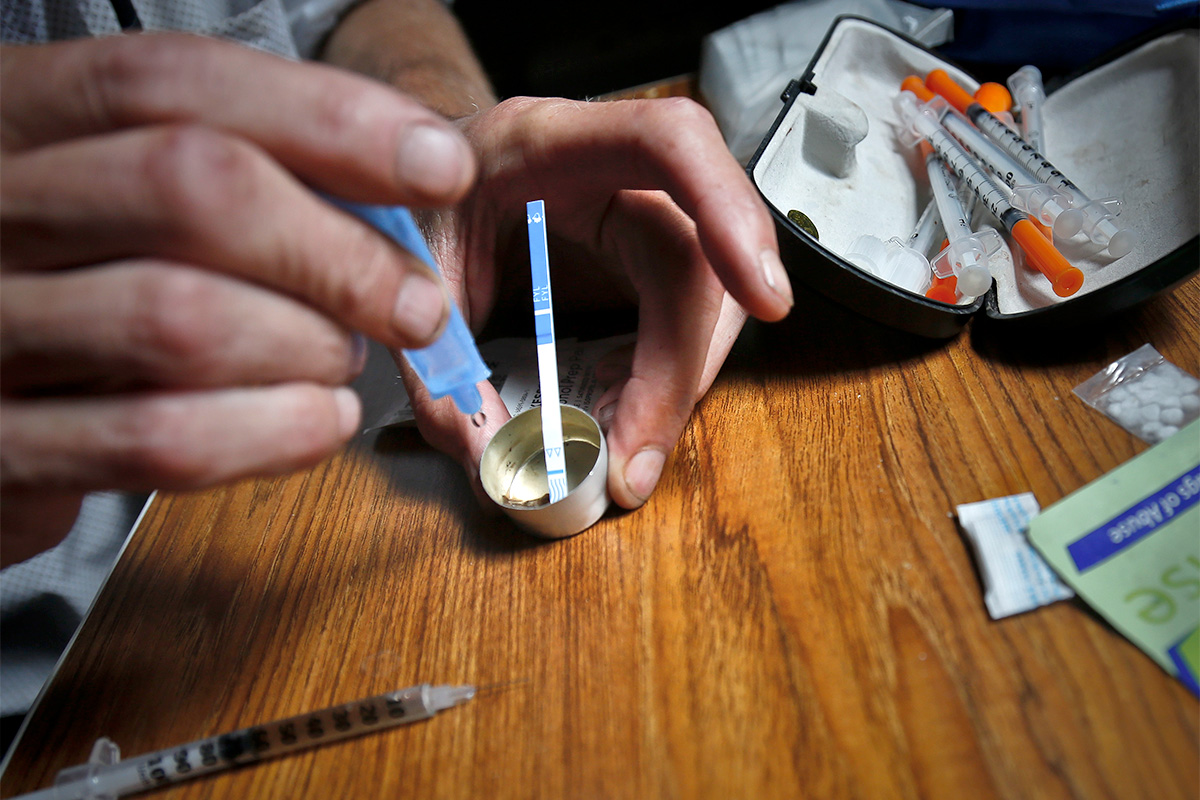 Closeup of hands using a fentanyl test strip to test drugs