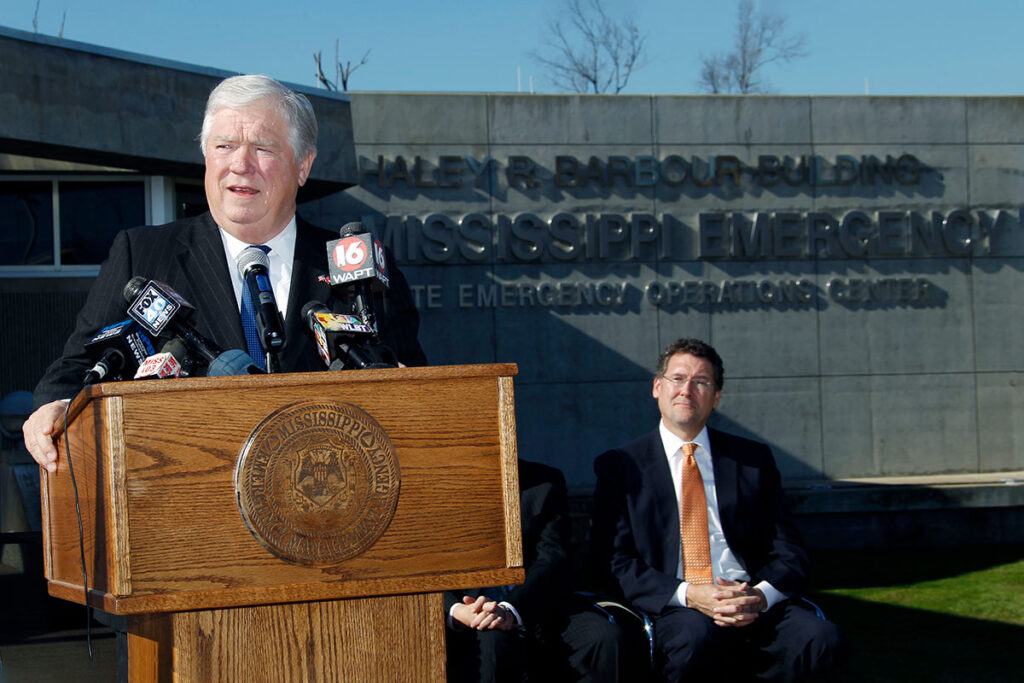 Haley Barbour speaks at a podium in front of the Mississippi Emergency Management Agency headquarters which is named after him
