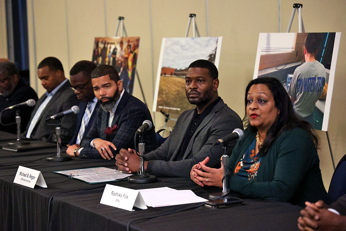 A row of people sitting at a table including Chokwe Lumumba and EPA administer Michael Regan