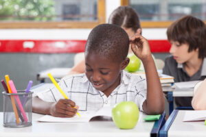 black boy writing in classroom setting (school board elections)