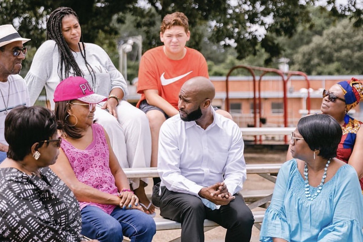 a photo of a man with a group of people sitting around him outdoors