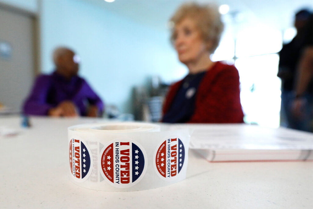 a photo of a roll of I Voted Stickers and several women standing behind a table